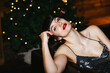 © BONNINSTUDIO/Stocksy - Alluring lady sitting on sofa during Xmas party
