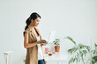 © Marc Tran/Stocksy - Asian woman holding a laptop working in the office portrait