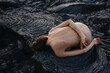 © Anastasia Mihaylova (Shpara)/Stocksy - Nude female lying on black solid lava field in Iceland