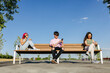 © VICTOR TORRES/Stocksy - Absent friends sitting on bench and using cellphones