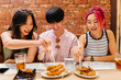 © VICTOR TORRES/Stocksy - Smiling chinese friends enjoying delicious japanese food in restaurant