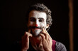 © Albert Martinez/Stocksy - Serious and sad clown forcing a smile