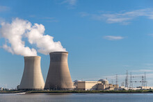 Antwerpen, Flanders, Belgium - July 10, 2022: Landscape, Cooling Towers Blowing Steam In Blue Air In Evening, And Doel Nuclear Power Plant Buildings, Seen From Scheldt River