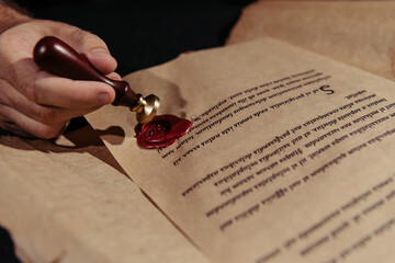 Poster - close up view of manuscript with wax seal near cropped monk isolated on black.