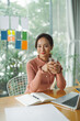 © Marc Tran/Stocksy - Young business woman drinking water using laptop working from home