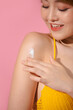 © Marc Tran/Stocksy - Beautiful woman applying body lotion on her shoulder.