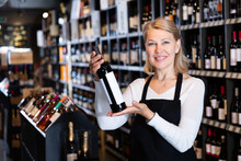 Portrait Of Confident Middle Aged Woman Owner Of Wine Store Offering To Buy Bottled Wine..