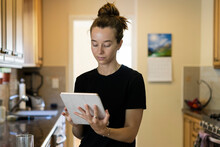 Young Woman Checks Her Ipad In The Kitchen At Home In The Morning