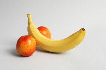 Wall Mural - Banana and nectarines symbolizing male genitals on light grey background. Potency concept