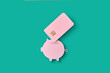 © Yaroslav Danylchenko/Stocksy - Papercraft piggy bank and pink credit card.