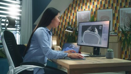 Asian female freelancer working from home office and creating 3D prototype of modern VR headset in professional 3D modeling software using pc and digital tablet