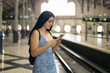 © Pedro Merino/Stocksy - Girl waiting for the train at the station using smartphone