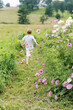 © Serena Burroughs/Stocksy - Little boy running through meadow by pink flowers in summer