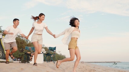 Happy friends holding hands running enjoy life funny and freedom on sand at beach together to sea in holiday vacation time at sunset, Young Asian group woman and man in summer travel, people lifestyle