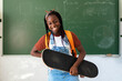 © Santi Nuñez/Stocksy - Portrait of Student holding a skateboard