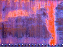 Peeling Blue, Orange And Purple Paint Over Rusty Metal