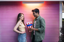 Couple Sharing Popcorn Against Pink Wall