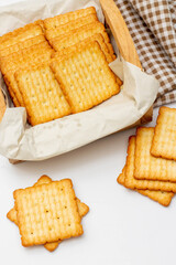 Wall Mural - Snack concept, Salty crackers or biscuits are arranged in rows on paper and wooden container