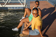 © Lupe Rodríguez/Stocksy - young black female friends sitting on a jetty