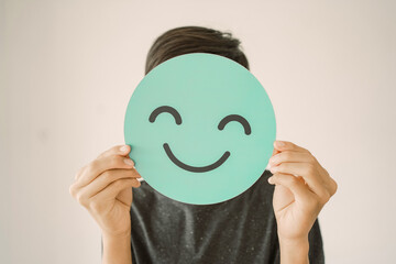 Wall Mural - Happy mixed Asian teen boy holding smile emoji face, positive mental health concept