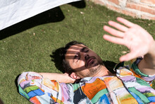 Man Covering His Face From Sun While Lying On Grass.