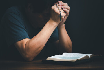 Man reading holy bible book and folding hands pray to God.