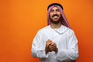 Wall Mural - Portrait of young smiling Arab man on orange background