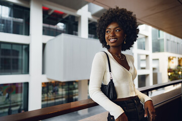 Portrait of young african woman with hairstyle standing at balcony and posing.