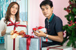 © themorningglory - Man giving  christmas present to his girlfriend and decorate christmas tree celebrate winter new year