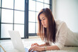 © themorningglory - Business asian woman lying on living room use laptop