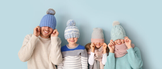 Wall Mural - Funny family in winter clothes on light blue background