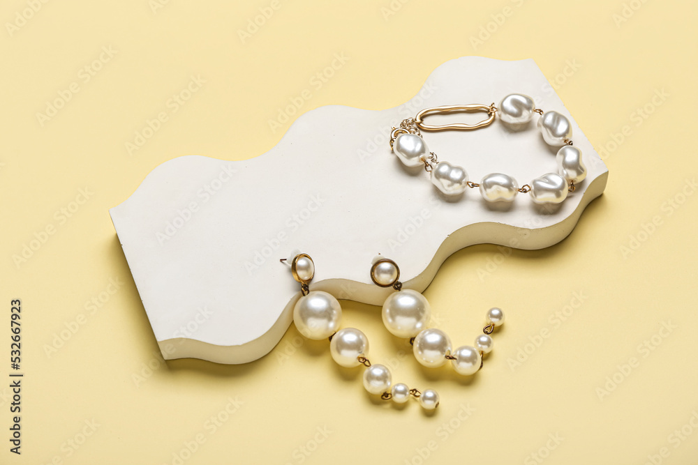 Showcase pedestal with pearl jewelry on color background
