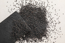 Board with scattered black sesame seeds on light background, closeup