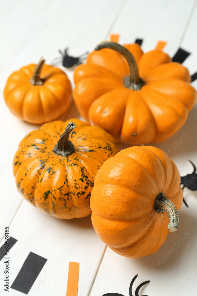 Halloween pumpkins with spiders on white wooden background, closeup