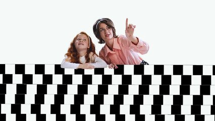 Wall Mural - Stop motion animation. Young woman and girl, mother and daughter sitting behind black and white optical illusion design, pattern over light background.