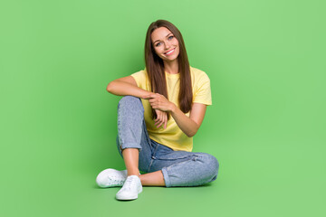 Wall Mural - Photo of pretty nice cute lady dressed stylish outfit sit floor chill good mood free time isolated on green color background