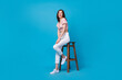 Full length photo of positive pretty lady stylish outfit sit comfort chair empty space good mood have fun isolated on blue color background