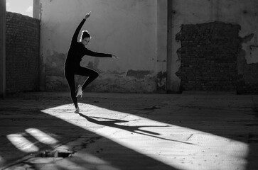 Wall Mural - Ballerina dancing in an abandoned building on a sunny day in black and white