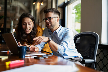 Colleagues laughing in office. Businesswoman and businessman drinking coffee.