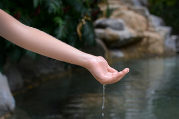 Wall Mural - Kid pouring water from hand in pond, closeup