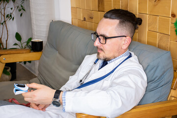 A doctor in a white medical coat at a appointment at home offers a patient with suspected pneumonia to use a pulseoximeter to measure pulse and blood oxygen saturation