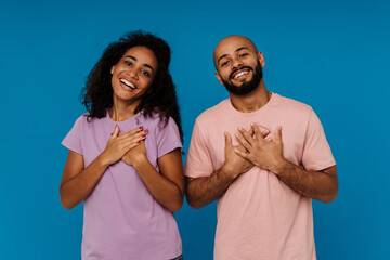 Black young man and woman holding their hands on chests