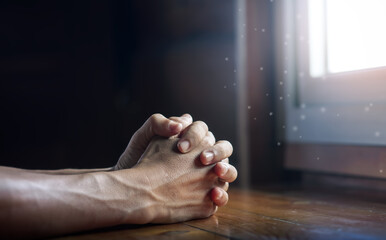 Wall Mural - Hands folded in prayer on wooden table with miracle light in church, concept for faith, spirituality and religion, with copy space , space for text