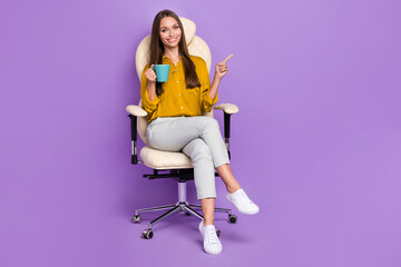 Wall Mural - Full size photo of pretty nice person sit chair arm hold coffee cup direct finger empty space isolated on violet color background