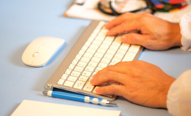 Wall Mural - Doctor uses a laptop computer and a digital tablet with a microscope. In a hospital laboratory, a doctor or technician records a lab test on a laptop computer.