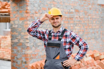 construction mason worker bricklayer installing red brick with trowel putty knife outdoors.