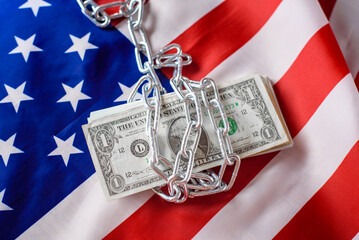 Chained American dollar bills, withheld from taxpayers for inflation, on American flag background.