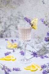 Wall Mural - Elegant glass of Sparkling Lavender Cocktail or mocktails surrounded by ingredients on gray table surface