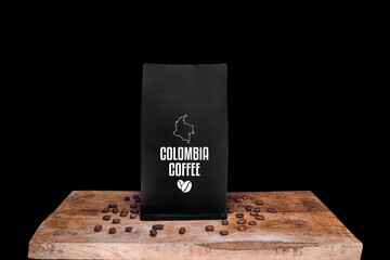 Wall Mural - Colombia coffee beans and black package on wooden board with black isolated background