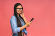© denis_vermenko - Happy Asian portrait beautiful cute young woman teen smiling excited typing text message on smart mobile phone enjoys online communication isolated on pink background with copy space.